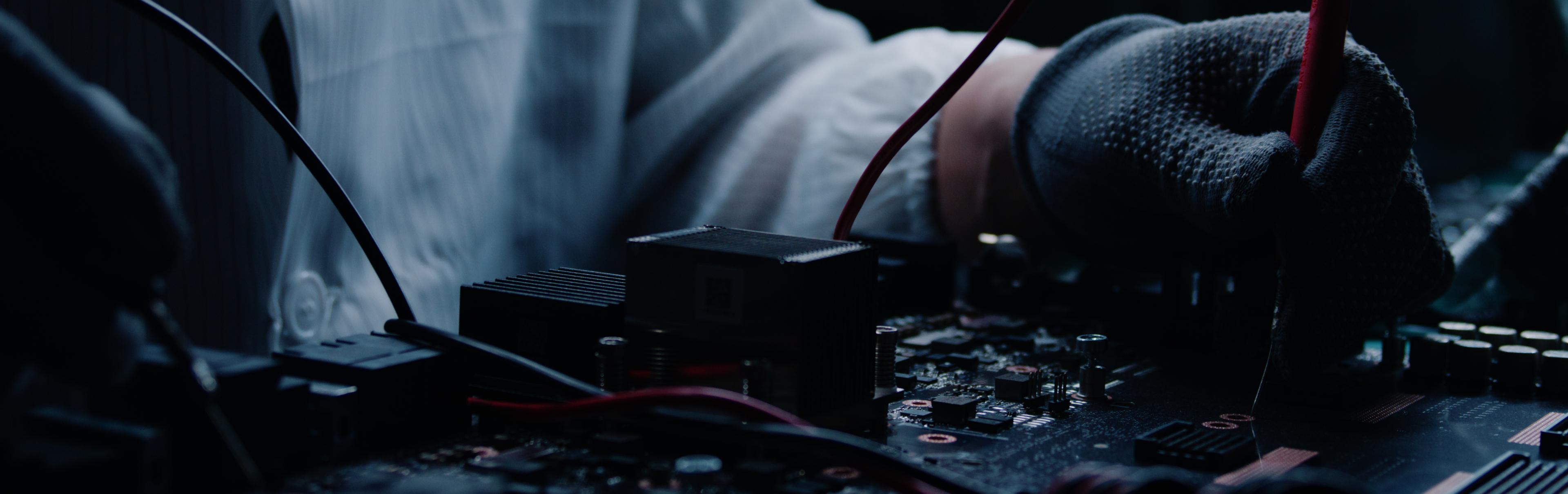 Bench camera view of an engineer inspecting a GPU board during filmed intake